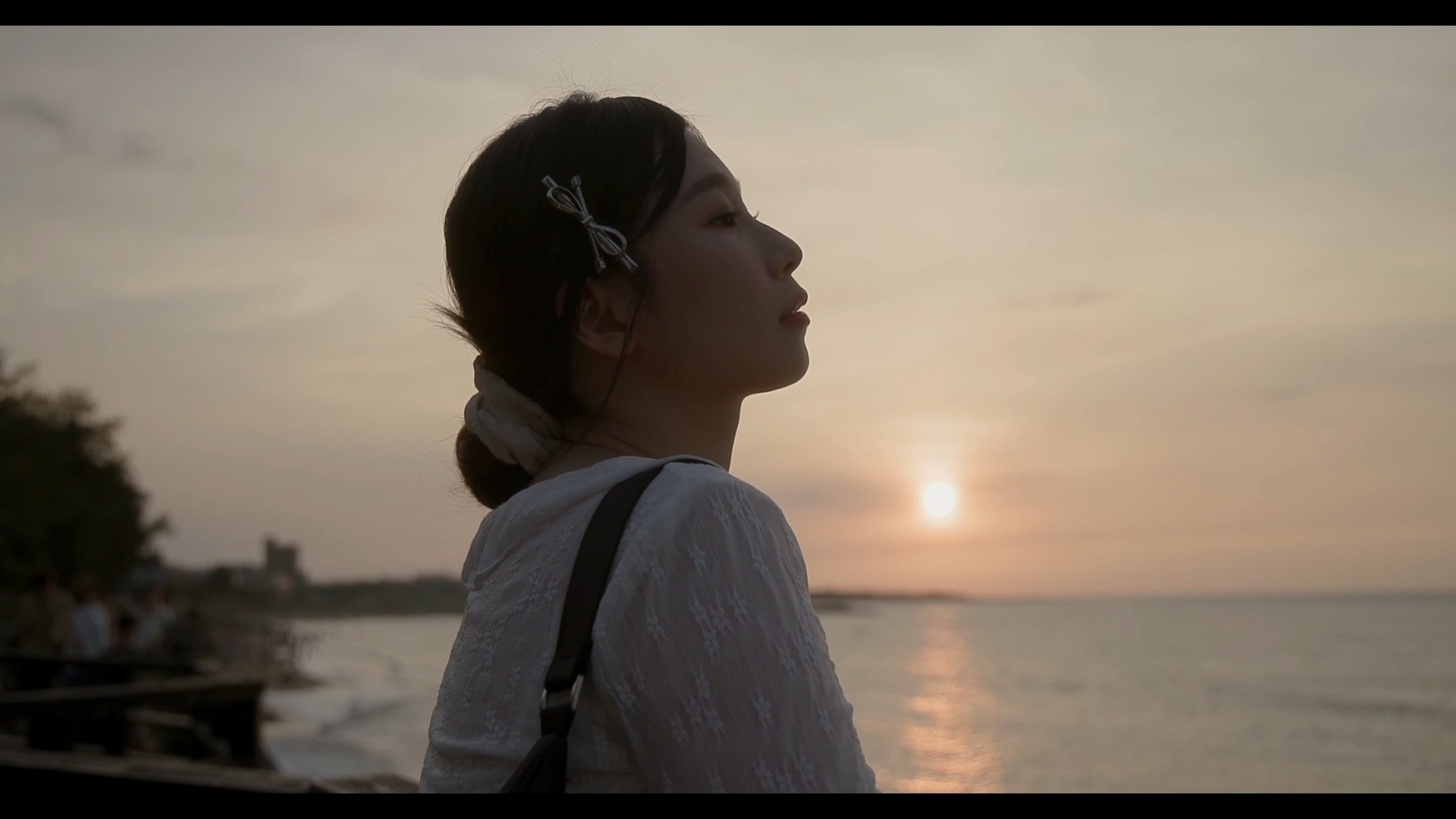 北海岸黃昏,側臉望向海面夕陽的人像影格。